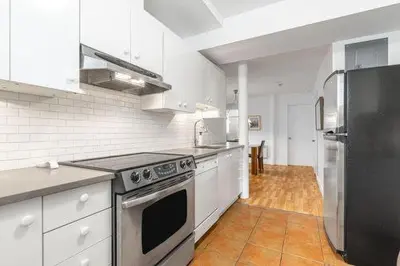 a kitchen with white appliances and a black refrigerator at Appartements Saint-Alexandre in Longueuil