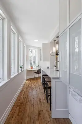 a kitchen with white walls and wooden floors and windows at Appartements Saint-Alexandre in Longueuil