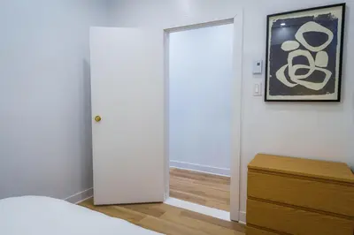 a bedroom with a white door and a wooden dresser at Ambiance Urbaine À Montréal in Montréal