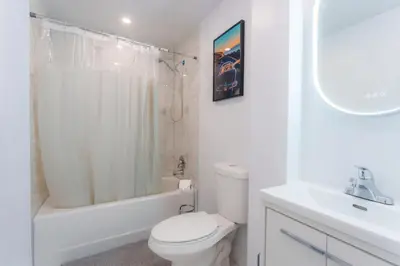 a white bathroom with a toilet and a sink at Ambiance Urbaine À Montréal in Montréal