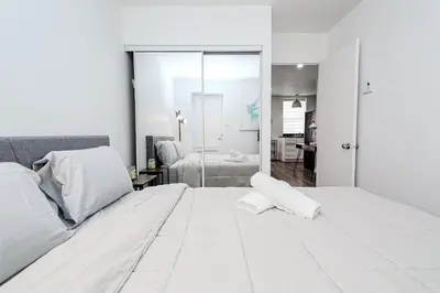 a white bedroom with a large white bed and a bathroom at Séjour pratique à Montréal, proche du vieux port in Montréal