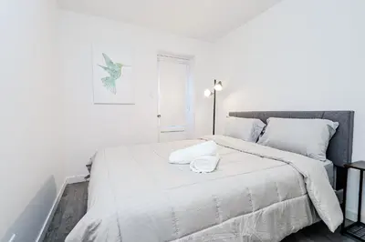 a white bedroom with a large bed with white sheets at Séjour pratique à Montréal, proche du vieux port in Montréal