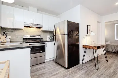 a kitchen with white cabinets and a stainless steel refrigerator at Séjour pratique à Montréal, proche du vieux port in Montréal