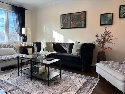 a living room with a black couch and a table at 4BR Townhouse 5-Min to DIX30 20-Min to Downtown in Brossard