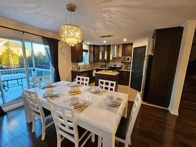 a kitchen and dining room with a white table and chairs at 4BR Townhouse 5-Min to DIX30 20-Min to Downtown in Brossard
