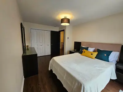 a bedroom with a large bed with blue and yellow pillows at 4BR Townhouse 5-Min to DIX30 20-Min to Downtown in Brossard