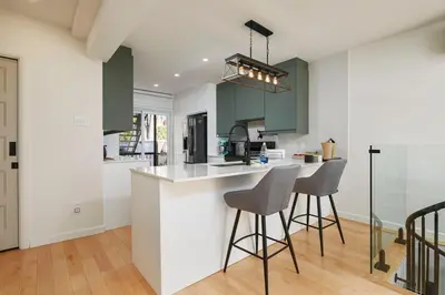 a kitchen with green cabinets and bar stools at Comfort & Style in Ahuntsic in Montréal