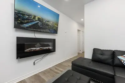 a living room with a black couch and a tv on a wall at Downtown Montreal Lofts Quartier des Spectacles in Montréal