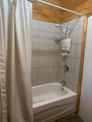 a bathroom with a tub and a shower curtain at Le Richelieu in Saint-Bernard-de-Lacolle