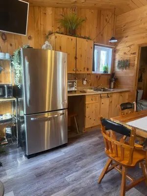 a kitchen with a stainless steel refrigerator and a table at Le Richelieu in Saint-Bernard-de-Lacolle