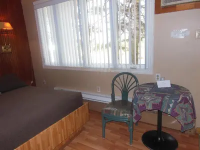 a bedroom with a bed and a chair and a table at Motel Le Paysan in Montréal