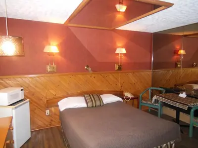 a bedroom with a bed and a table and a desk at Motel Le Paysan in Montréal