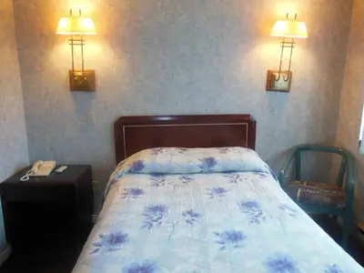 a bedroom with a bed and two lights on the wall at Motel Le Paysan in Montréal