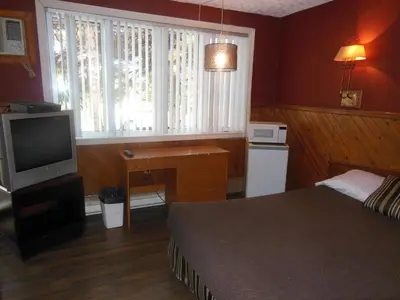 a bedroom with a bed and a tv and a window at Motel Le Paysan in Montréal