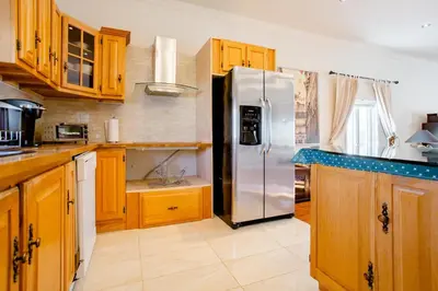 a kitchen with wooden cabinets and a stainless steel refrigerator at Luxury House Near Montreal Self Check-In in Longueuil