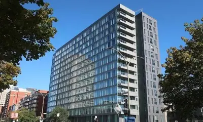 a tall building with glass windows on a city street at Highrise 1BDR Condo in Downtown Montreal - Long Term Stay by M11 in Montréal