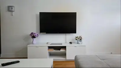 a living room with a tv on a white wall at Private rooms in a shared two bedrooms apartment in Montréal