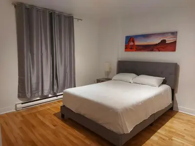 a bedroom with a bed and a large window at Private rooms in a shared two bedrooms apartment in Montréal