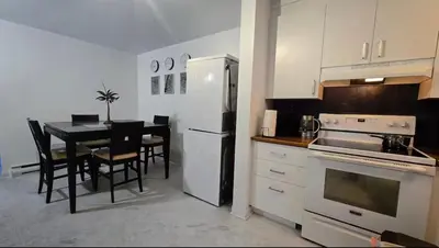 a kitchen with a table and a white refrigerator at Private rooms in a shared two bedrooms apartment in Montréal