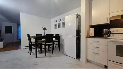 a kitchen with a dining table and a white refrigerator at Private rooms in a shared two bedrooms apartment in Montréal