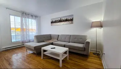 a living room with a couch and a table at Private rooms in a shared two bedrooms apartment in Montréal