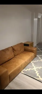a brown couch sitting in a living room at small modern 2 bedrooms in Montréal