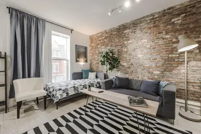 a living room with a couch and a brick wall at 4 bedrooms 2 floors Fully Renovated Apartment in Montréal