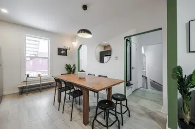 a dining room with a wooden table and stools at 4 bedrooms 2 floors Fully Renovated Apartment in Montréal