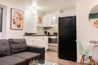 a living room with a couch and a black refrigerator at Griffintown Urban Nest 2BR Comfort in Montréal