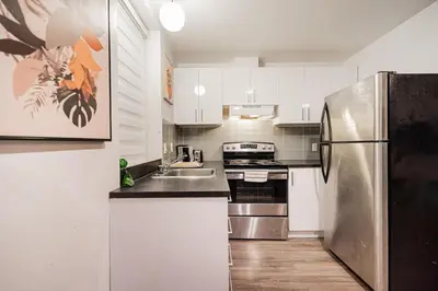 a kitchen with white cabinets and a stainless steel refrigerator at Griffintown Urban Nest 2BR Comfort in Montréal