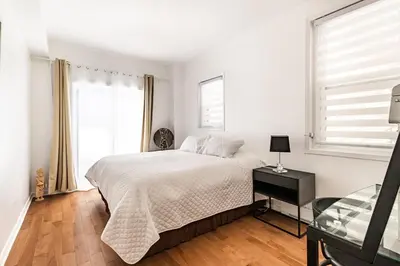 a white bedroom with a bed and a glass table at Au coeur du plateau in Montréal
