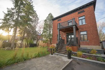 a brick house with a porch and a patio at Historical Home - Near Montreal in Longueuil