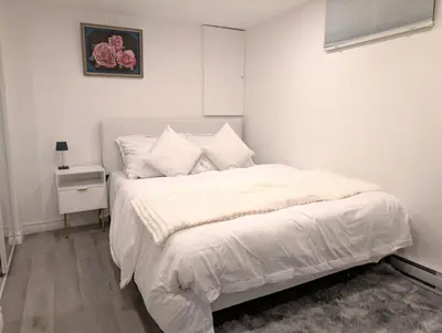 a bedroom with a bed with white sheets and a nightstand at Stylish & Modern Condo - FREE Parking & EV Chargers in Laval