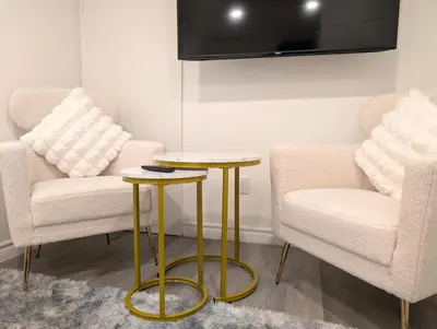 a living room with two chairs and two tables at Stylish & Modern Condo - FREE Parking & EV Chargers in Laval