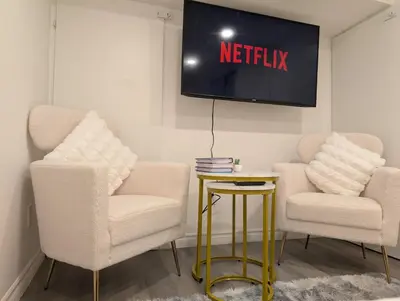 two chairs and a tv with a netflix sign on the wall at Stylish & Modern Condo - FREE Parking & EV Chargers in Laval