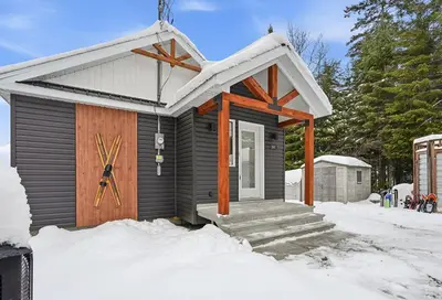a small house with a wooden door in the snow at 232 on the Lake Ski, Golf, Snowmobile in Adstock