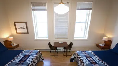 a bedroom with two beds and a table and windows at Motel De La Gare Richmond in Richmond