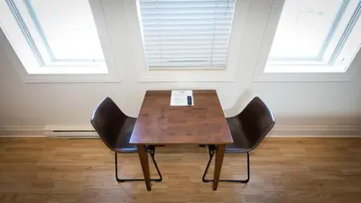 a table and two chairs in a room with two windows at Motel De La Gare Richmond in Richmond