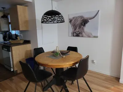 a dining room table with chairs and a cow on the wall at L'EMERAUDE sur la rivière Magog in Sherbrooke