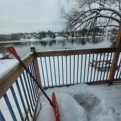 a snow shovel on a porch with a view of a lake at L'EMERAUDE sur la rivière Magog in Sherbrooke