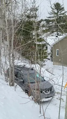 a car parked in the snow in front of a house at L'EMERAUDE sur la rivière Magog in Sherbrooke