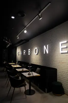 a restaurant with tables and chairs and a sign on the wall at Carbone in Montréal