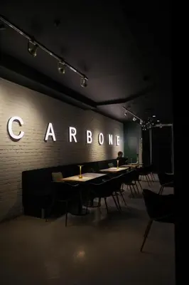 a restaurant with tables and chairs and a sign on a wall at Carbone in Montréal