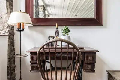 a table with a chair and a lamp and a mirror at Unique 1847 Heritage Retreat - Garden - 2 Parkings in Montréal