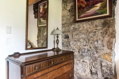 a room with a dresser and two mirrors on a stone wall at Unique 1847 Heritage Retreat - Garden - 2 Parkings in Montréal