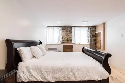 a bedroom with a large bed with white sheets at Unique 1847 Heritage Retreat - Garden - 2 Parkings in Montréal
