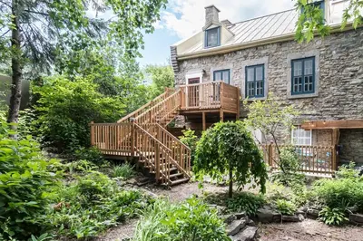 a house with a wooden staircase in the yard at Unique 1847 Heritage Retreat - Garden - 2 Parkings in Montréal