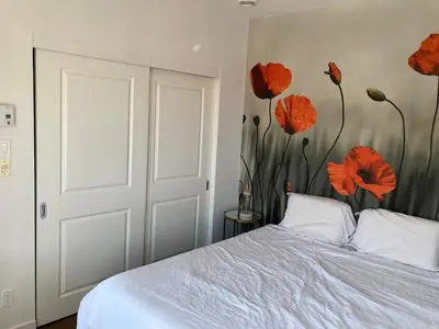 a bedroom with a bed with red flowers on the wall at Beautiful bright apartment in Montréal