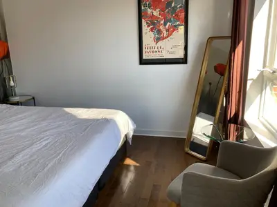 a bedroom with a bed and a chair and a mirror at Beautiful bright apartment in Montréal
