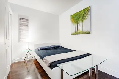 a white bedroom with a bed and a glass table at Magnifique appartement Montréal Centre-Ville in Montréal